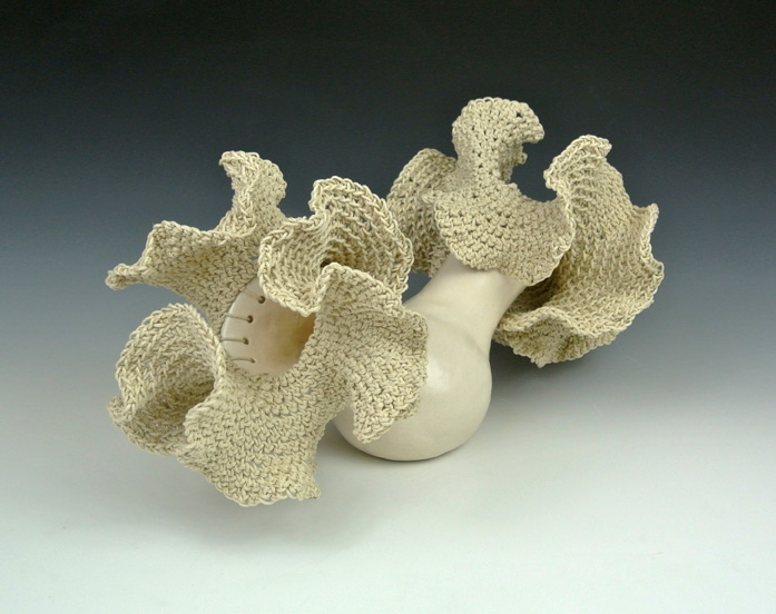Ceramic sculpture of a hyperbolic crocheted form on a ceramic base.