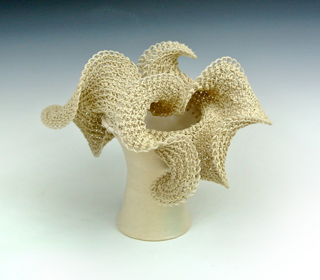 Ceramic sculpture of a hyperbolic crocheted form on a ceramic base.